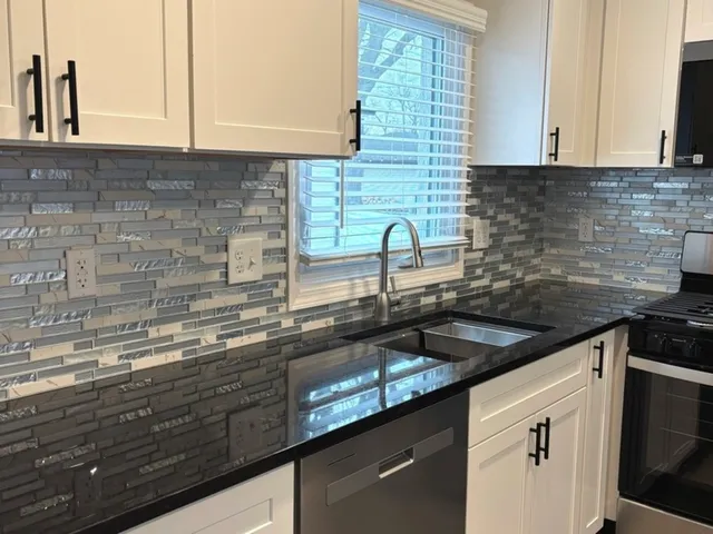 a kitchen with granite countertop a sink a stove and cabinets