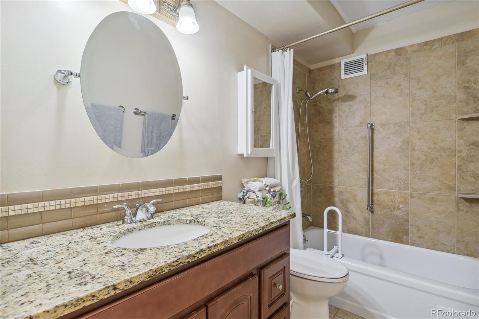 9655 Center Avenue, Unit 5A Denver, CO 80247 - Photo 15 of 45 a bathroom with a granite countertop sink a toilet and a mirror
