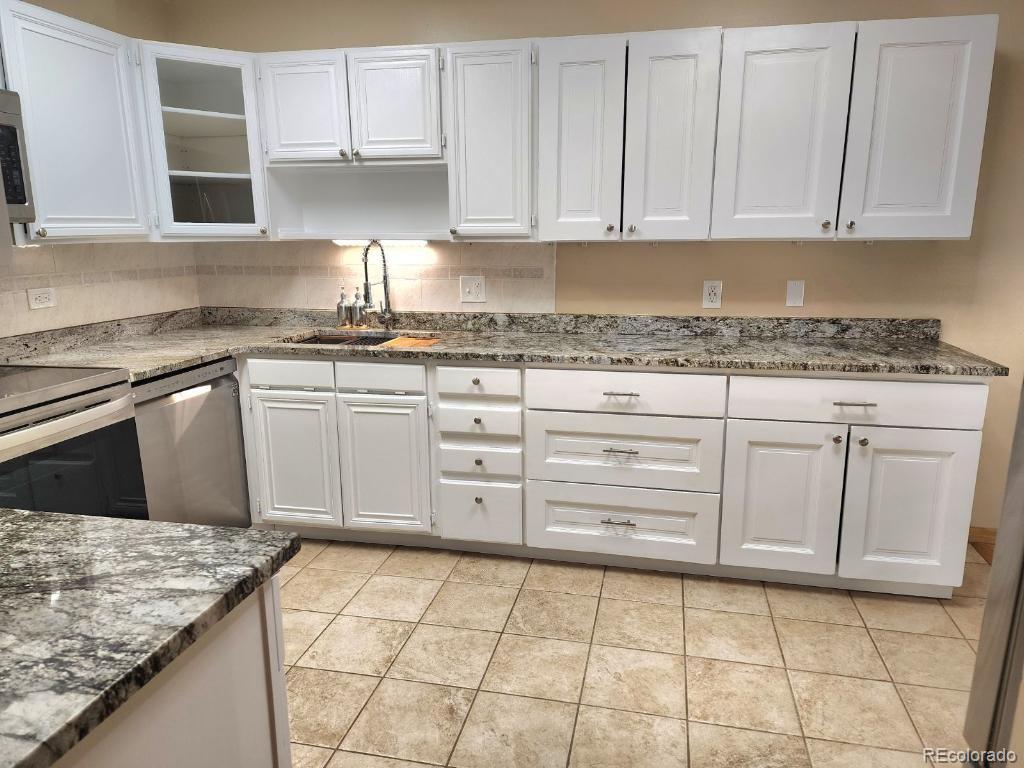 9655 Center Avenue, Unit 5A Denver, CO 80247 - Photo 4 of 45 a kitchen with granite countertop white cabinets and stainless steel appliances
