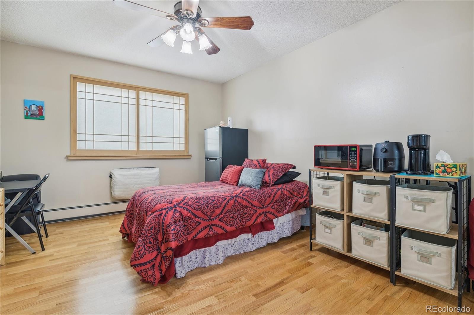 9655 Center Avenue, Unit 5A Denver, CO 80247 - Photo 10 of 45 a bedroom with a bed and a bookshelf with wooden floor