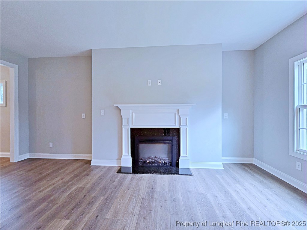 425 Shawcroft Road Fayetteville, NC 28311 - Photo 8 of 50 an empty room with wooden floor fireplace and windows