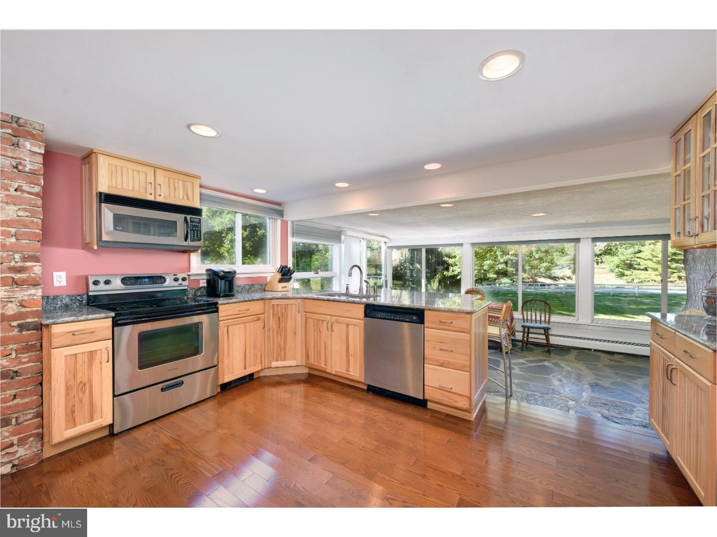 500 Gulph Road Wayne, PA 19087 - Photo 8 of 25 a kitchen with stainless steel appliances kitchen island granite countertop a stove a sink dishwasher and a microwave with wooden floor