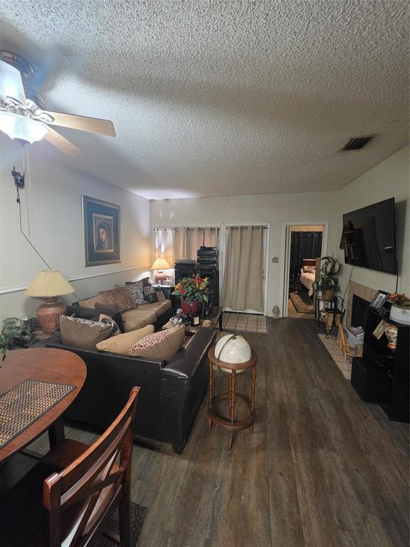 13219 Emily Road, Unit 4104 Dallas, TX 75240 - Photo 4 of 7 Living area featuring wood-look flooring, a ceiling fan, and a fireplace