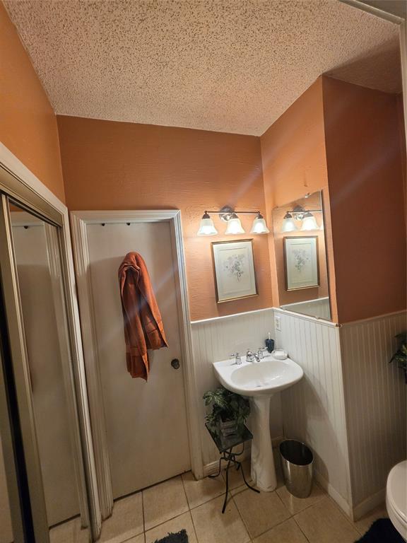 13219 Emily Road, Unit 4104 Dallas, TX 75240 - Photo 5 of 7 The bathroom features a pedestal sink, white wainscoting, and tile flooring
