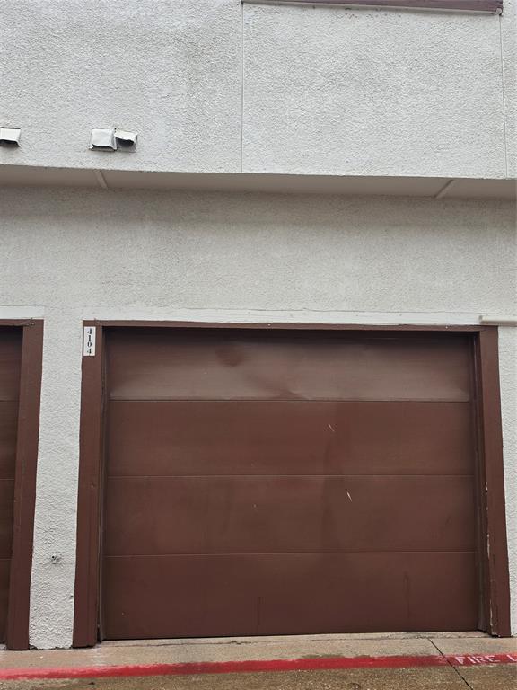 13219 Emily Road, Unit 4104 Dallas, TX 75240 - Photo 7 of 7 The property features a brown garage door set into a textured, light-colored exterior wall