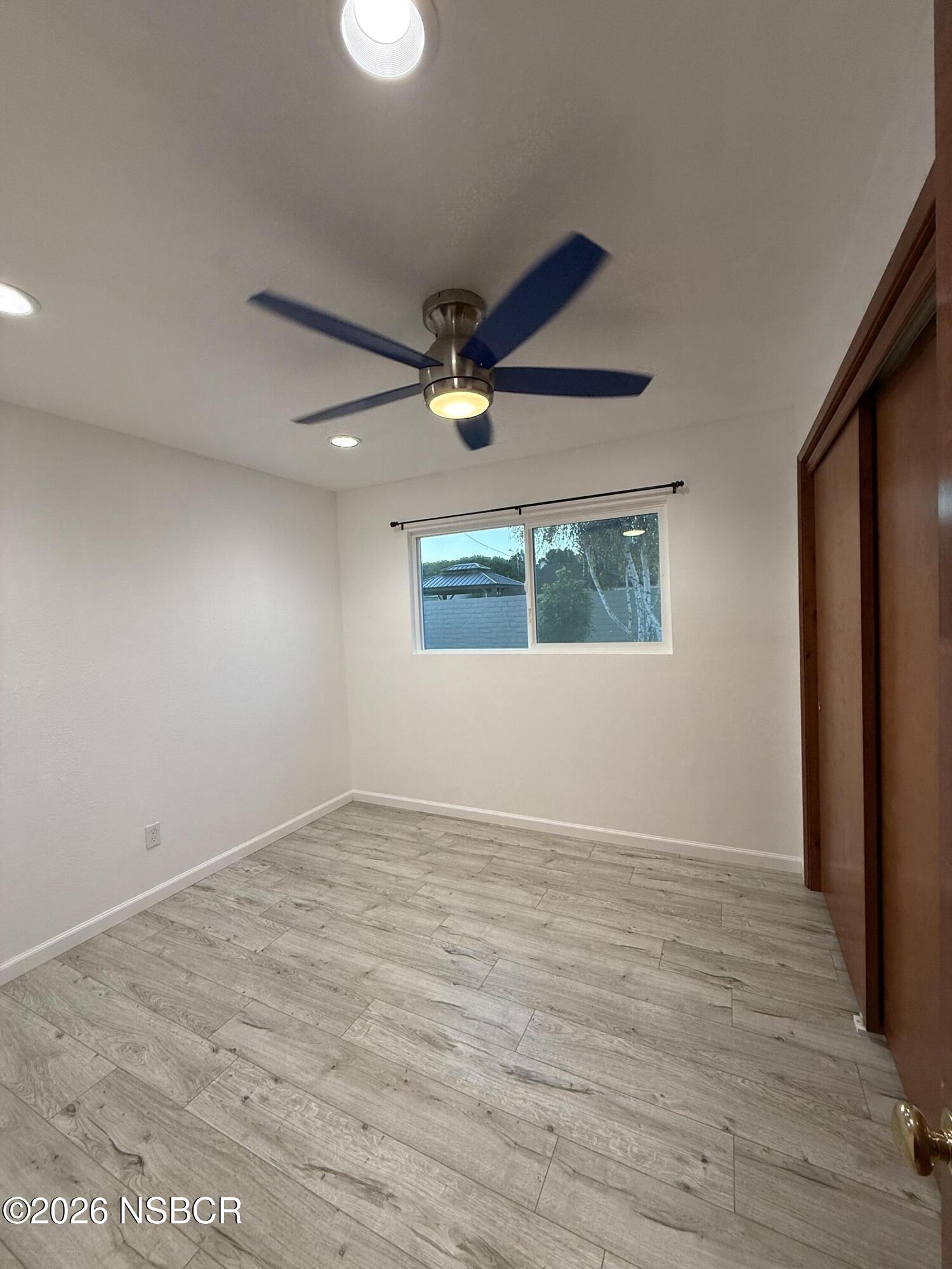 1408 West Walnut Avenue Lompoc, CA 93436 - Photo 17 of 27 an empty room with wooden floor fan and windows
