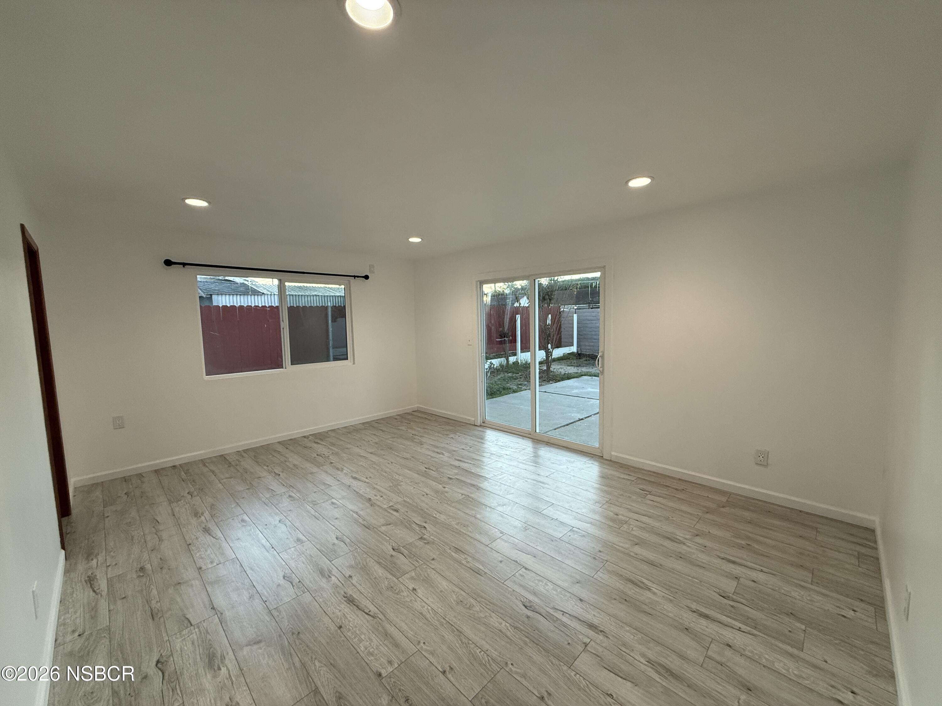 1408 West Walnut Avenue Lompoc, CA 93436 - Photo 3 of 27 an empty room with wooden floor and windows