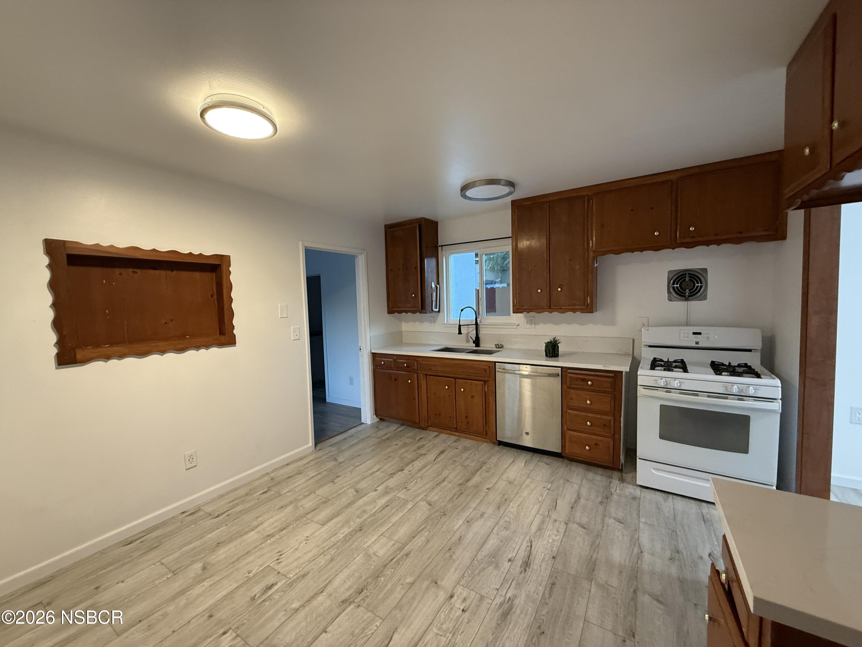 1408 West Walnut Avenue Lompoc, CA 93436 - Photo 4 of 27 a kitchen with a sink cabinets and wooden floor