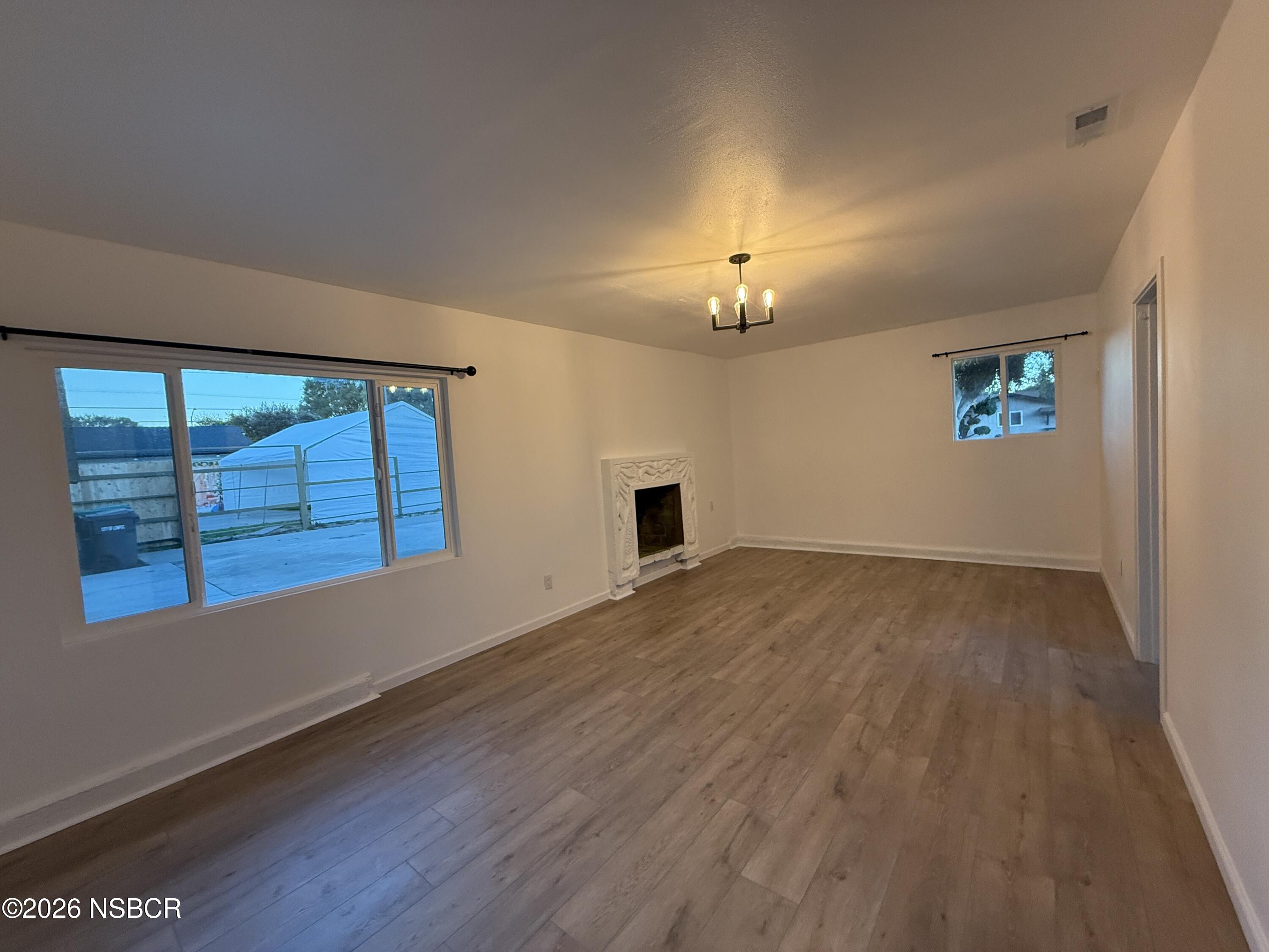 1408 West Walnut Avenue Lompoc, CA 93436 - Photo 8 of 27 a view of an empty room with a window and wooden floor