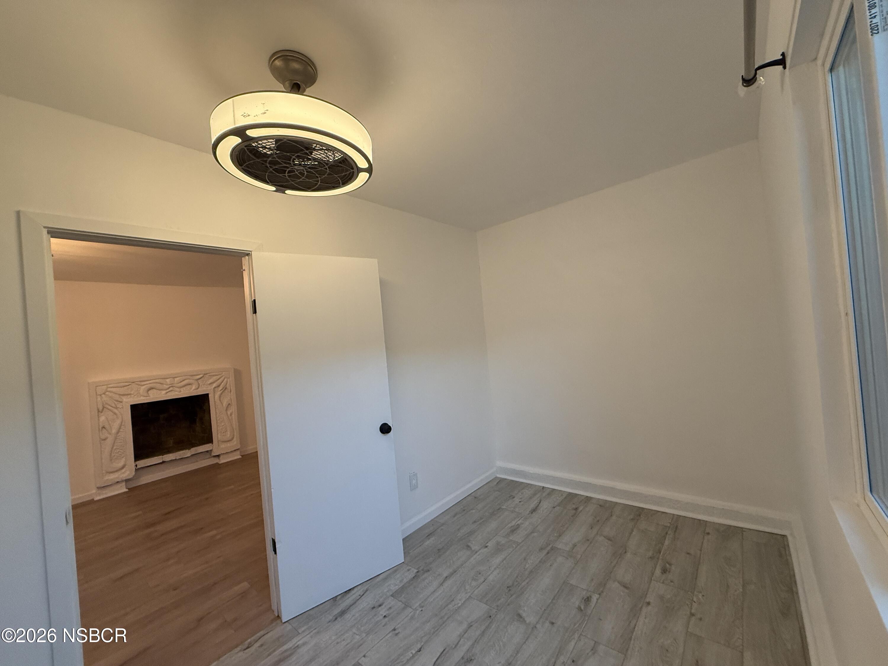 1408 West Walnut Avenue Lompoc, CA 93436 - Photo 10 of 27 a view of an empty room with wooden floor and a window