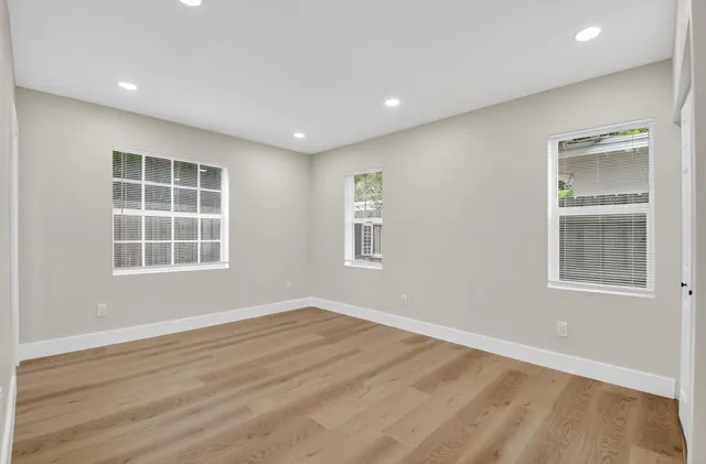 a view of an empty room with wooden floor and windows