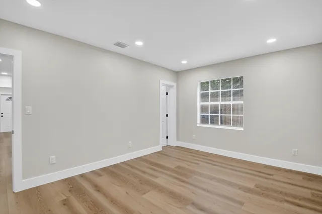 an empty room with wooden floor and windows