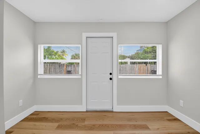 a view of an empty room with wooden floor and a window
