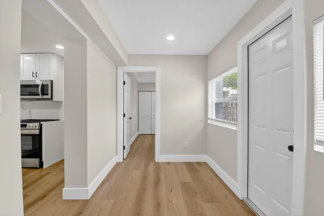 a view of a hallway with wooden floor and a living room