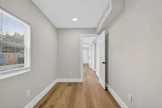 a view of a hallway with wooden floor and a window