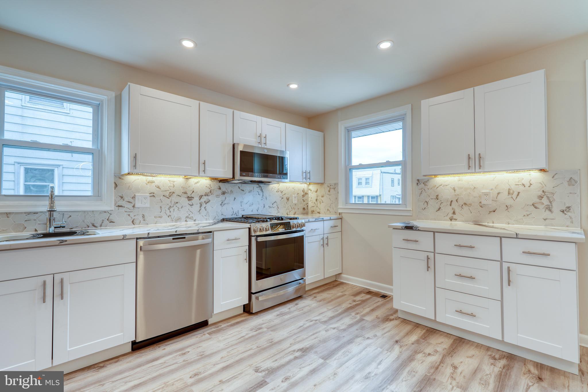 9939 Medway Road Philadelphia, PA 19115 - Photo 6 of 43 a kitchen with granite countertop white cabinets and white appliances