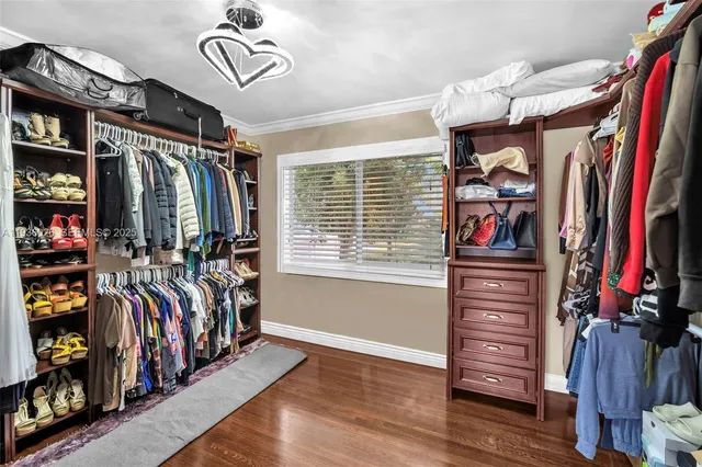 a view of walk in closet with clothes and shoes