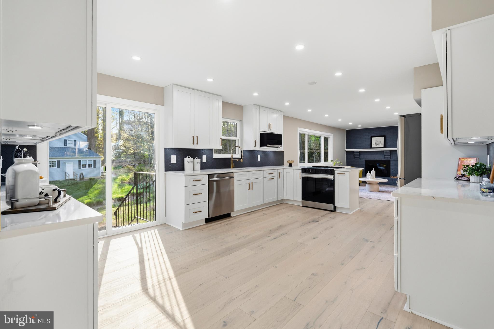 1840 Post Oak Trail Reston, VA 20191 - Photo 11 of 46 a large white kitchen with stainless steel appliances granite countertop a large counter top a stove a refrigerator a sink dishwasher and a fireplace with wooden floor