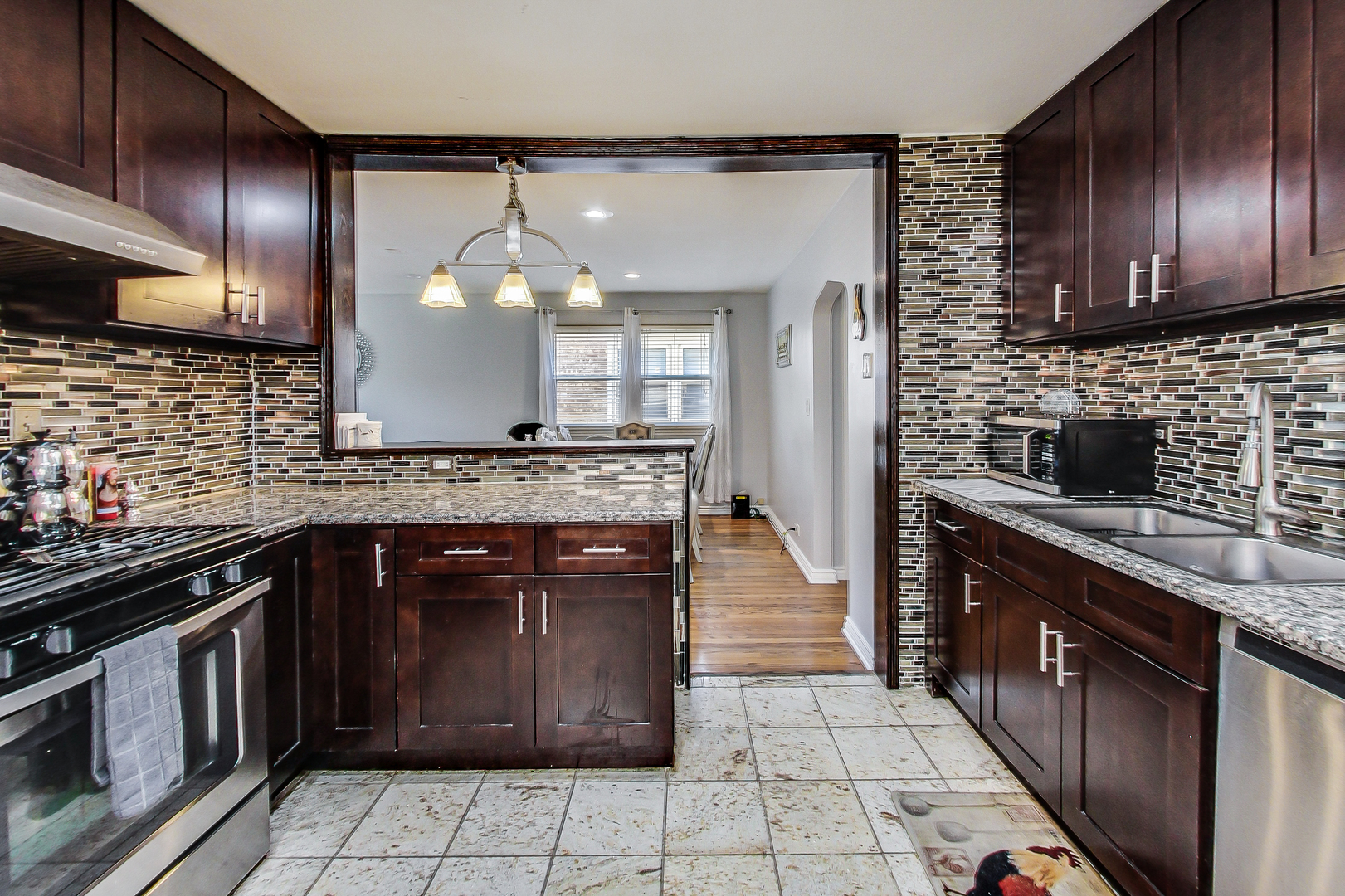 Undisclosed Address Chicago, IL 60625 - Photo 12 of 30 a kitchen with stainless steel appliances granite countertop a stove a sink and a microwave