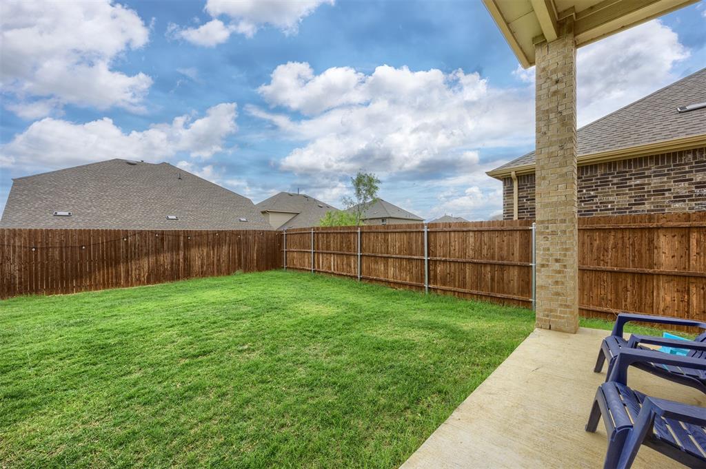 3808 High Country Road Aubrey, TX 76227 - Photo 23 of 38 Expansive backyard featuring a manicured lawn, a stained wood privacy fence, and a covered concrete patio supported by a brick column