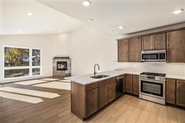 a kitchen with stainless steel appliances granite countertop wooden cabinets a sink a stove a microwave and island