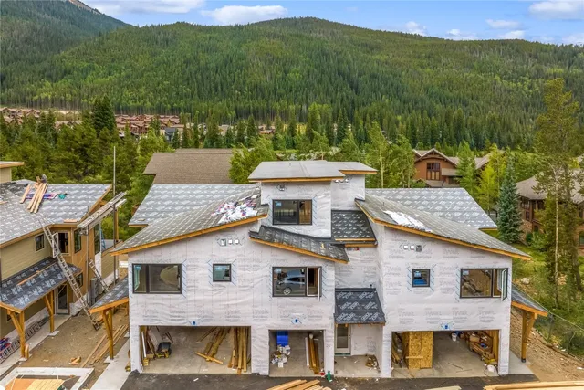 a front view of a house with a yard and mountain view in back