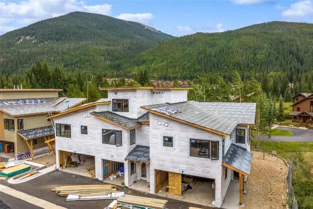 a view of a white house next to a big yard with large trees
