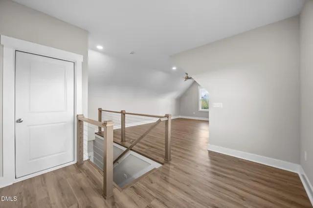 a view of an empty room with wooden floor and a kitchen