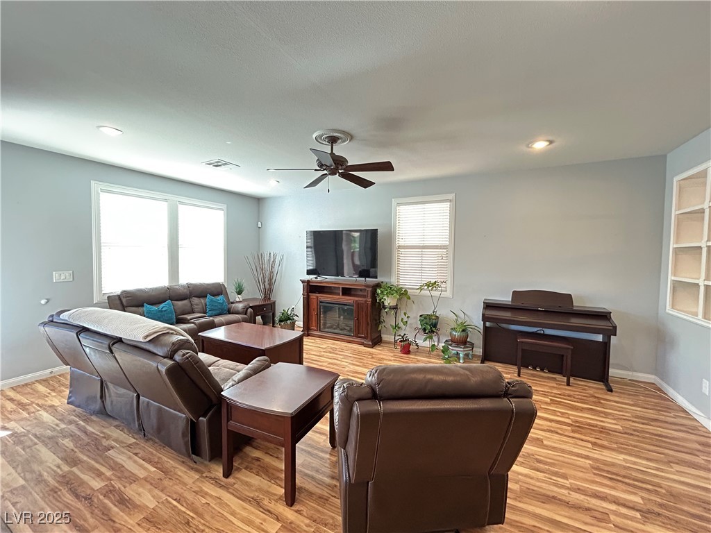 5553 Fairmeade Way Las Vegas, NV 89135 - Photo 6 of 42 Living room featuring healthy amount of natural light, light wood-style flooring, ceiling fan, a glass covered fireplace, and recessed lighting