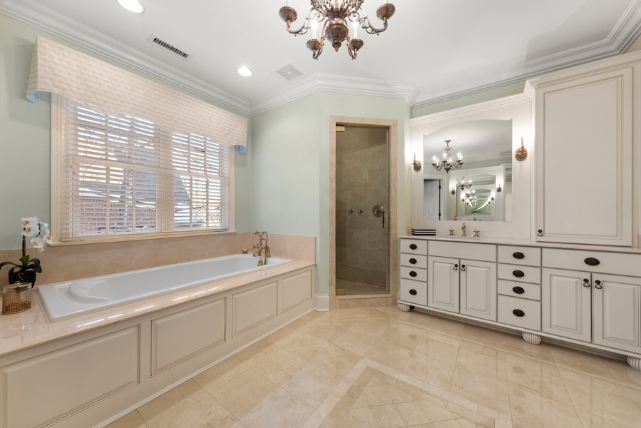 711 South County Line Road Hinsdale, IL 60521 - Photo 21 of 42 a spacious bathroom with a double vanity sink a large mirror and a bathtub with shower