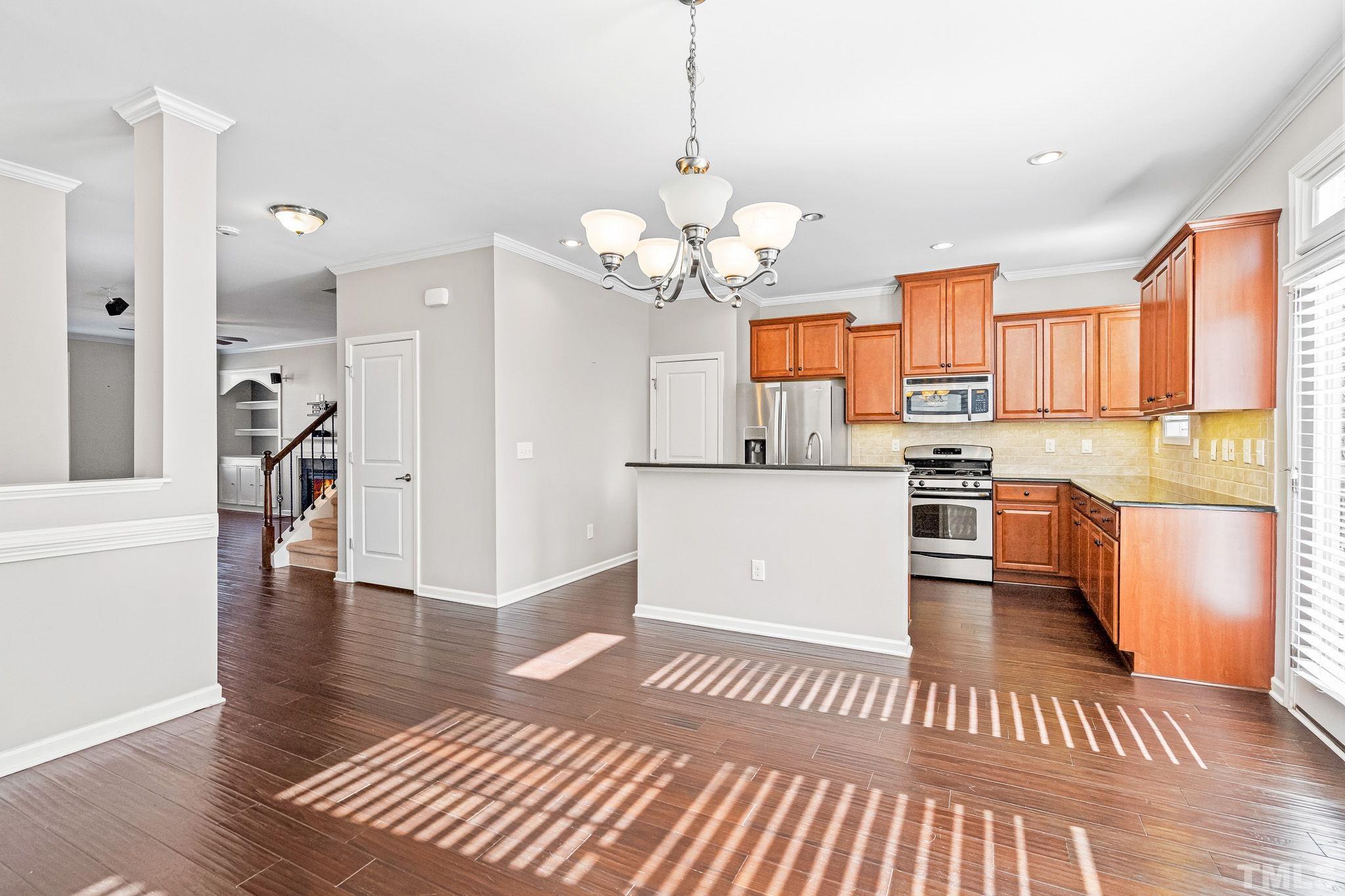 5637 Wade Park Boulevard Raleigh, NC 27607 - Photo 13 of 37 a open kitchen with stainless steel appliances granite countertop a refrigerator a sink dishwasher a dining table and chairs with wooden floor