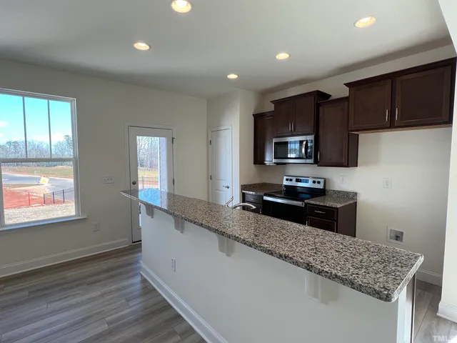 a kitchen with granite countertop stainless steel appliances a stove top oven a sink and dishwasher