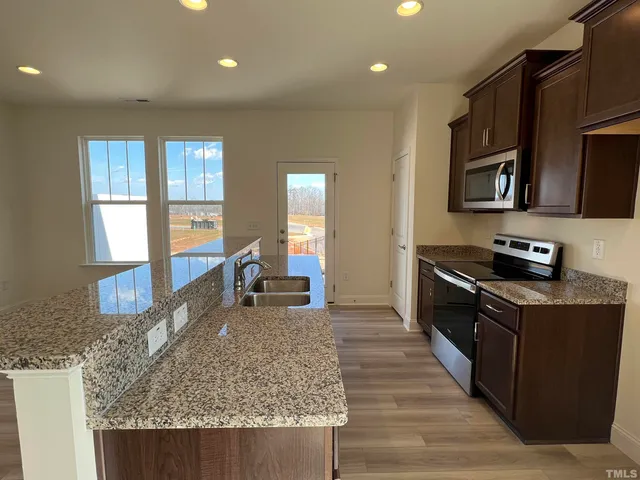 a kitchen with stainless steel appliances granite countertop a stove a sink and a microwave