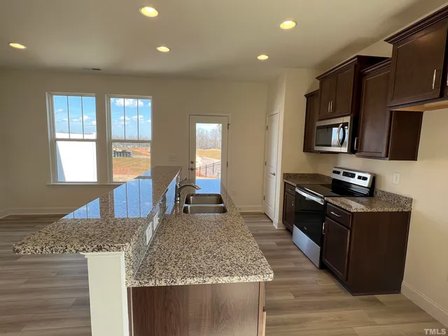 a kitchen with stainless steel appliances granite countertop a stove a sink and a microwave