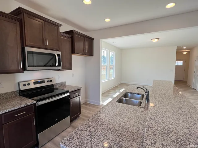 a kitchen with granite countertop a stove microwave and sink