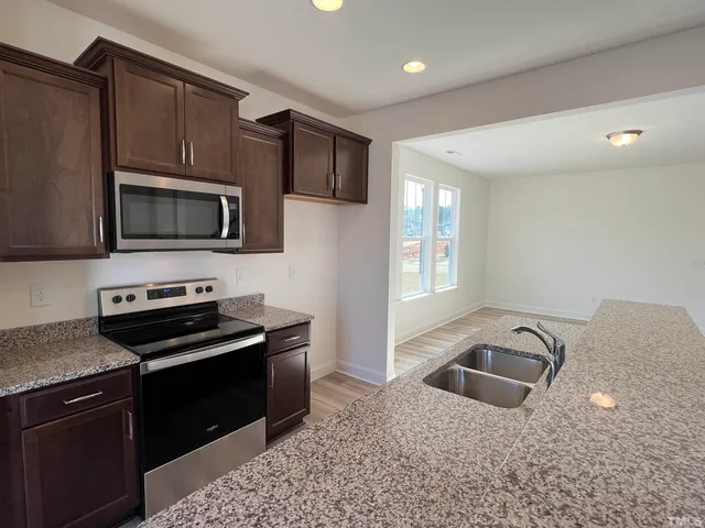 a kitchen with granite countertop a stove top oven microwave and refrigerator