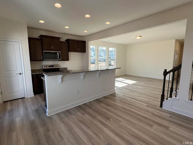 a kitchen with stainless steel appliances granite countertop a sink a stove and a wooden floors
