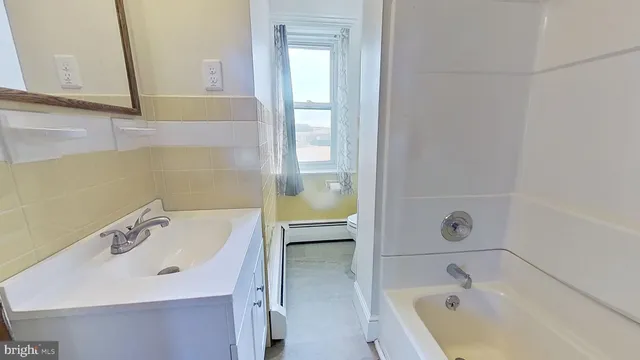 a bathroom with a tub sink and mirror