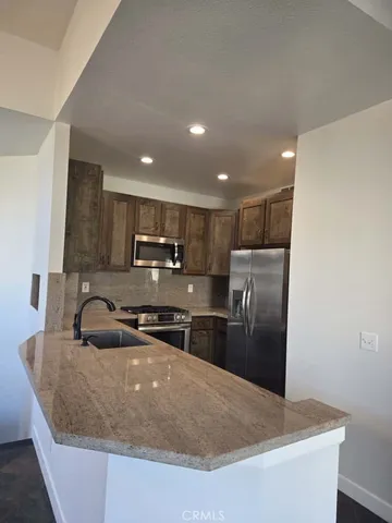 a kitchen with stainless steel appliances granite countertop a sink a stove a microwave a refrigerator a washer and dryer