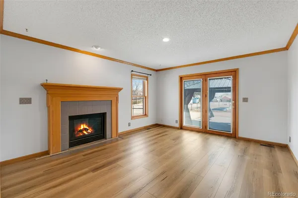 a view of an empty room with wooden floor fireplace and a window