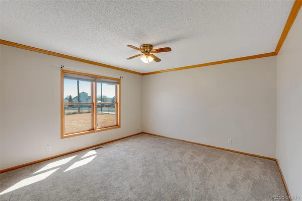 an empty room with chandelier fan and windows