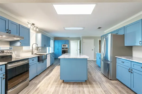 a kitchen with stainless steel appliances kitchen island granite countertop wooden floors and a sink
