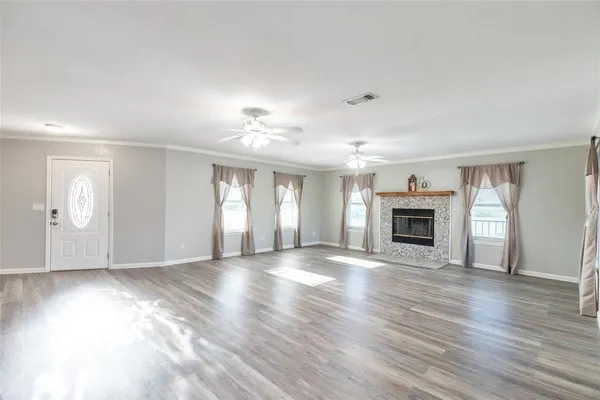 an empty room with wooden floor fireplace and windows