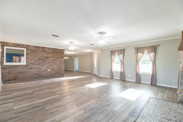 a view of an empty room with window and wooden floor