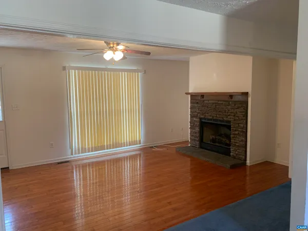 an empty room with wooden floor fireplace and windows