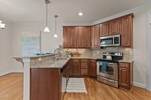 a kitchen with stainless steel appliances granite countertop a stove top oven a sink dishwasher and a microwave oven on the wooden floor