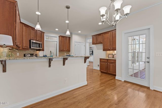 a view of kitchen with stainless steel appliances granite countertop a stove top oven a refrigerator a sink and dishwasher with wooden floor