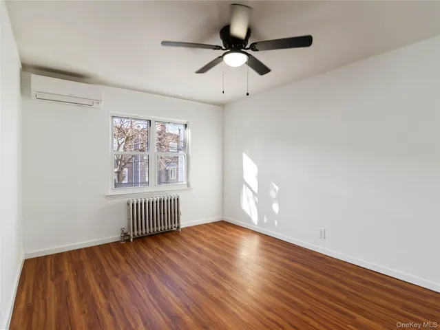 an empty room with wooden floor chandelier fan and windows