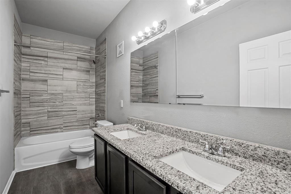 609 Meadow View Court, Unit 102 Denton, TX 76207 - Photo 11 of 13 a bathroom with a granite countertop sink a toilet a mirror and shower