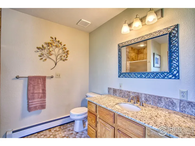 a bathroom with a granite countertop sink a toilet and a mirror